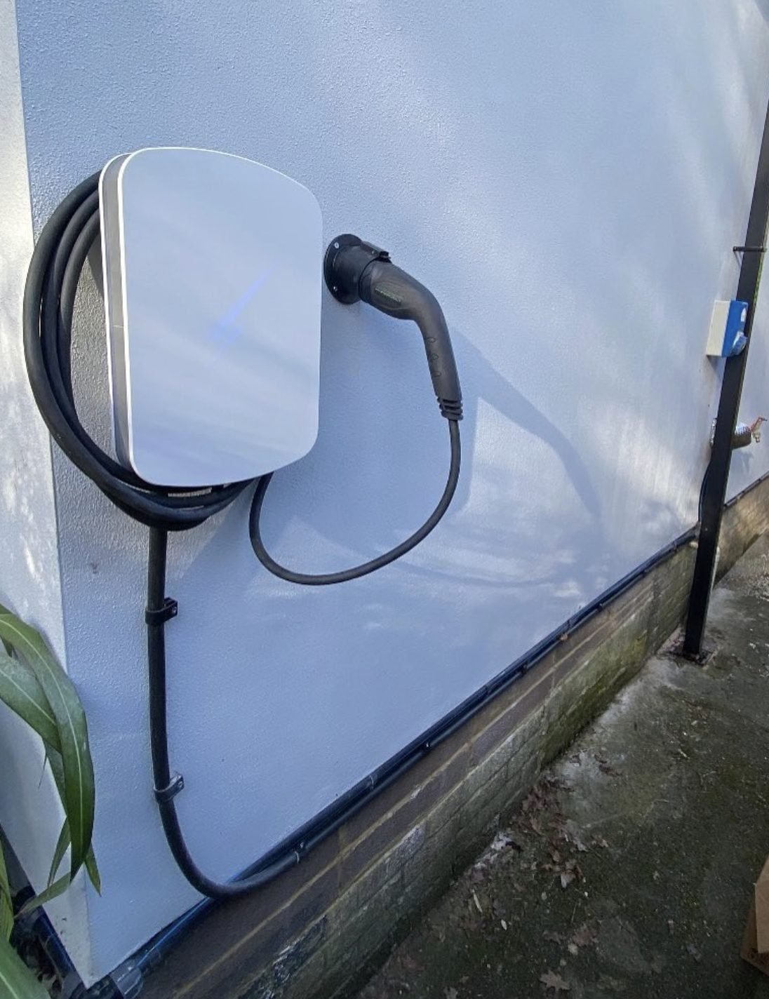EV charge point on a rendered wall with the lead coiled