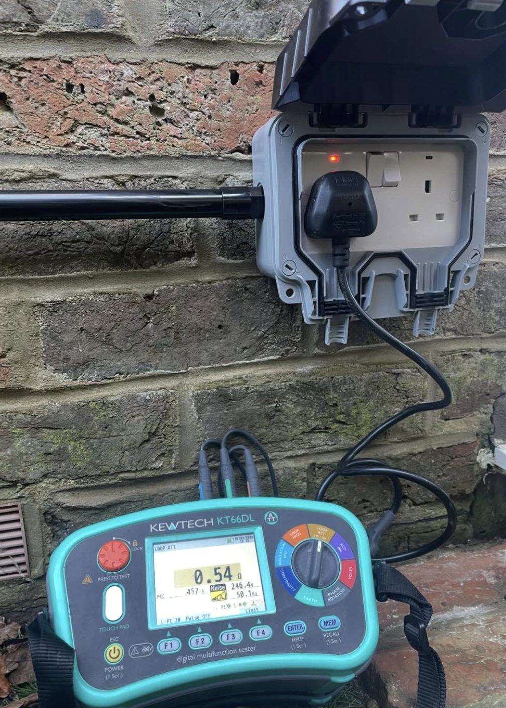 Digital multifunction tester showing an earth loop reading at an outdoor socket